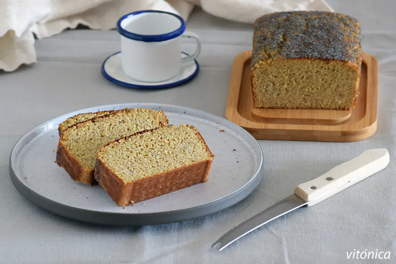 Rebanadas de bizcocho sin azucar con semillas de amapola, servidas en un plato gris junto a una taza y un cuchillo.