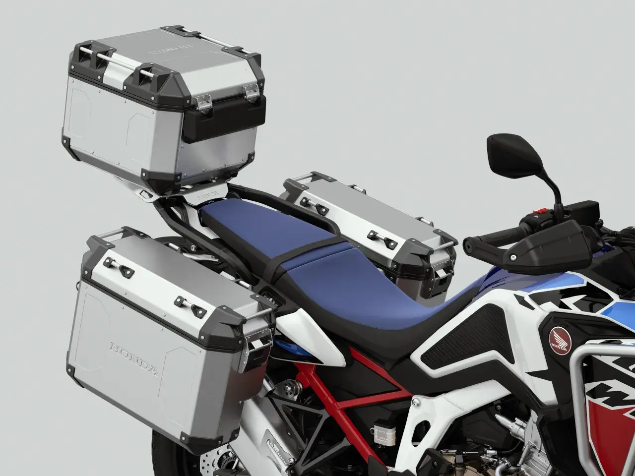 Detalle de una moto Honda con tres maletas de equipaje plateadas, listas para una aventura.