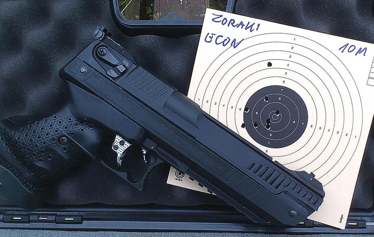 Pistolet Zoraki HP-01 Ultra obok tarczy strzeleckiej z widocznymi trafieniami na 10 metrów.