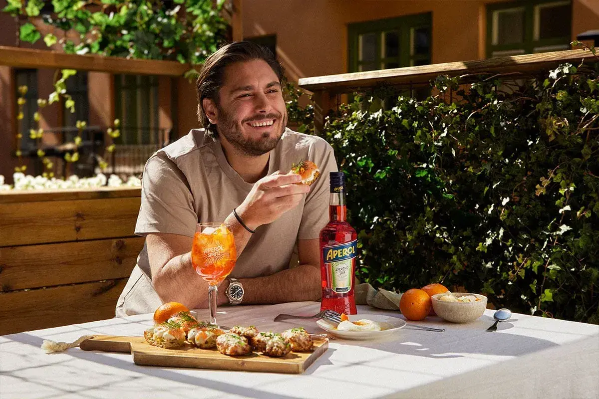 Man njuter av en Aperol Spritz och tilltugg utomhus.