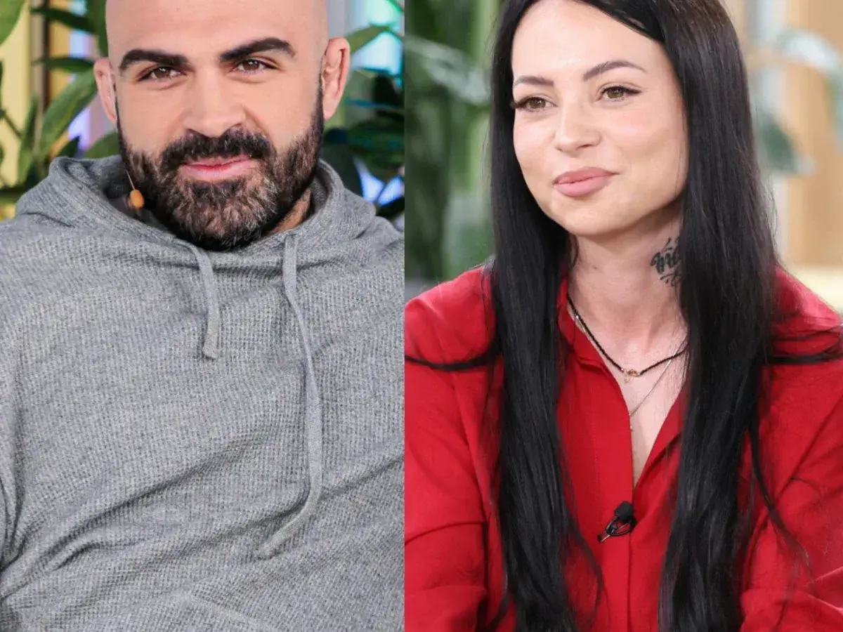 Akop i Sylwia Szostak, uśmiechnięci i patrzący w różne strony. On w szarej bluzie, ona w czerwonej koszuli.