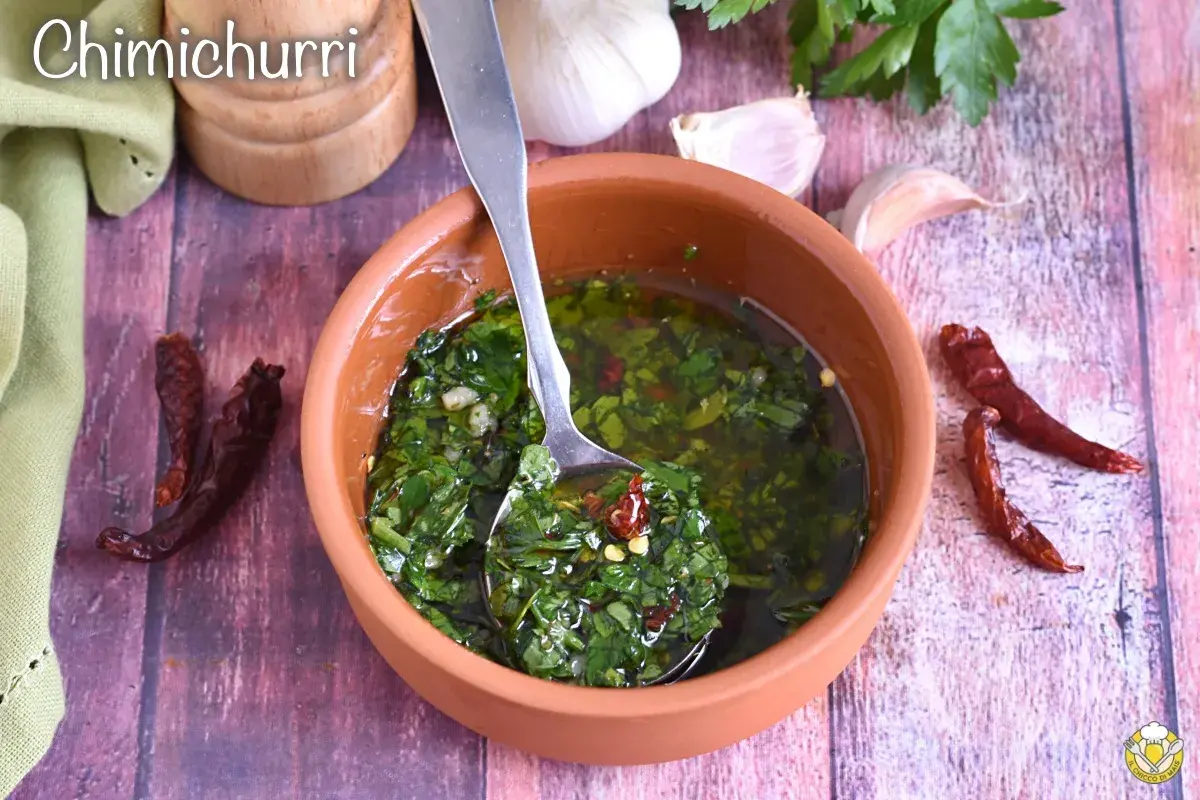 Salsa chimichurri fresca in ciotola di terracotta, con aglio, peperoncino secco e prezzemolo.