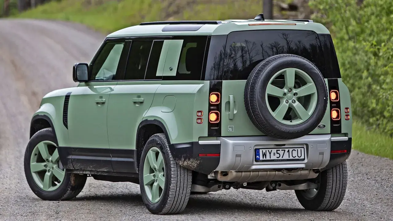 Zielony Land Rover Defender na szutrowej drodze, gotowy na przygodę.