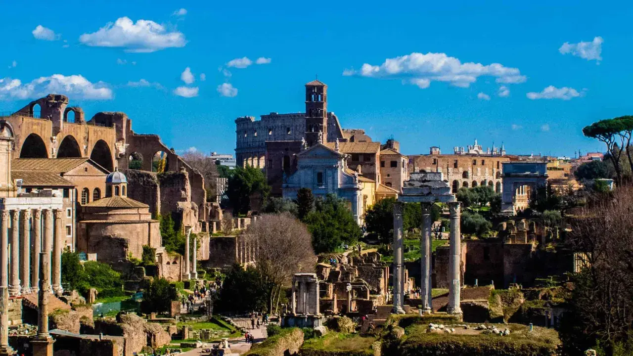 Il Foro Romano, un'istantanea di un viaggio a Roma 48h. Rovine antiche, il Colosseo e il cielo azzurro con nuvole bianche.
