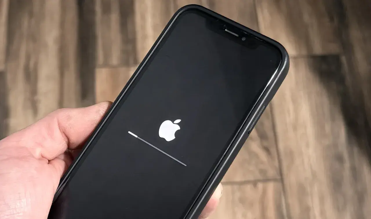 iPhone z logo Apple i paskiem postępu, aktualizacja iOS 26.3 w toku.