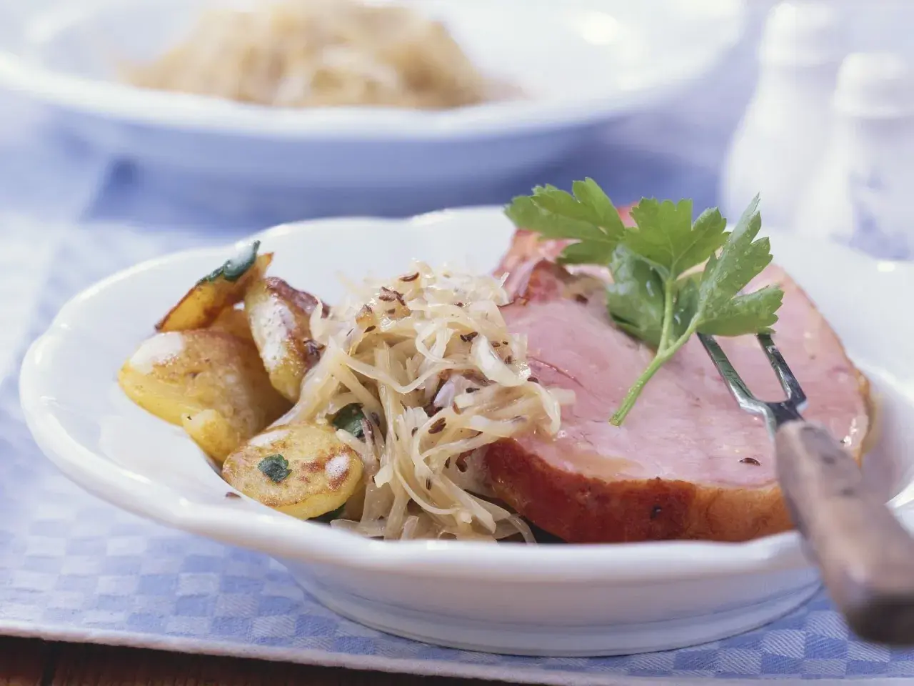 Herzhaftes Fleisch zu bayrisch Kraut mit Bratkartoffeln, garniert mit Petersilie. Ein Klassiker der bayerischen Küche.