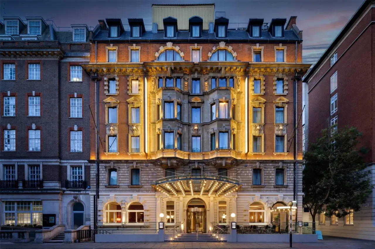 Elegancki hotel w Londynie z oświetloną fasadą i wejściem.
