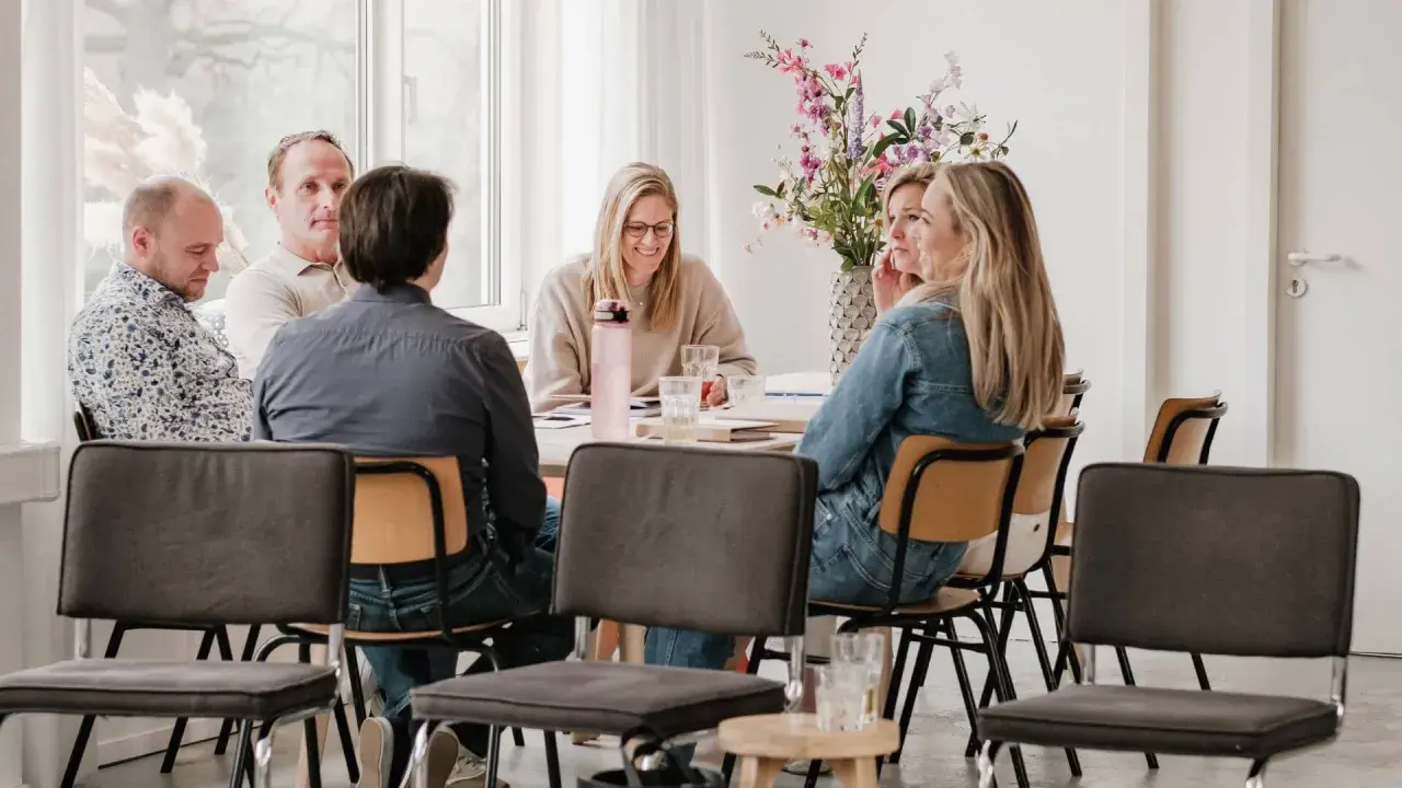 Groep mensen rond een tafel, met een intake formulier coaching op tafel.