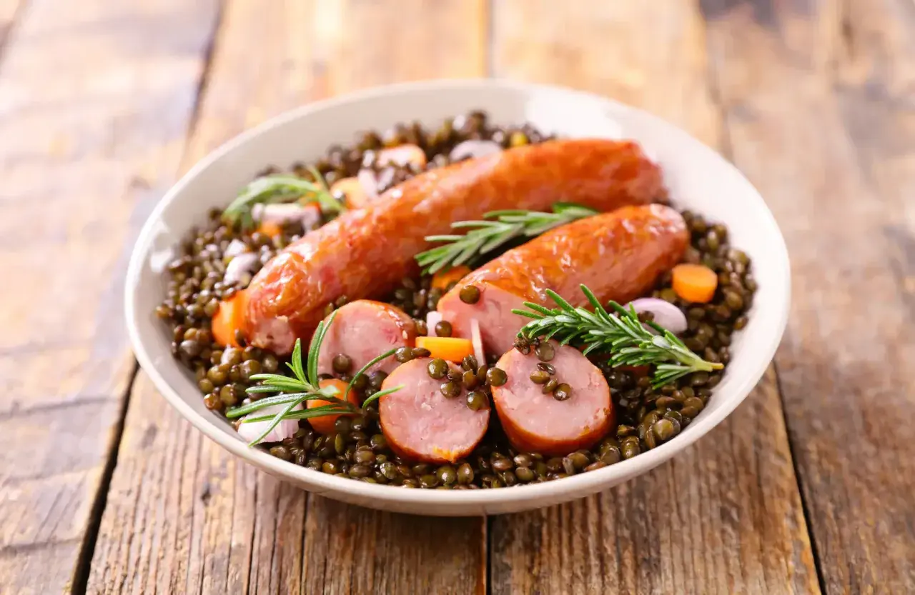 Saucisse lentille Cookeo : un plat réconfortant avec des saucisses savoureuses sur un lit de lentilles, carottes et romarin.