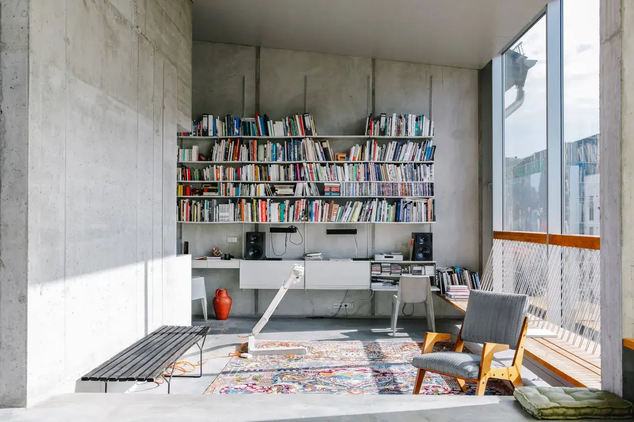 Ein bunter, detailreicher Perserteppich bildet einen warmen Kontrast zur kühlen Betonarchitektur und zeigt, wie man einen Perserteppich modern kombinieren kann.