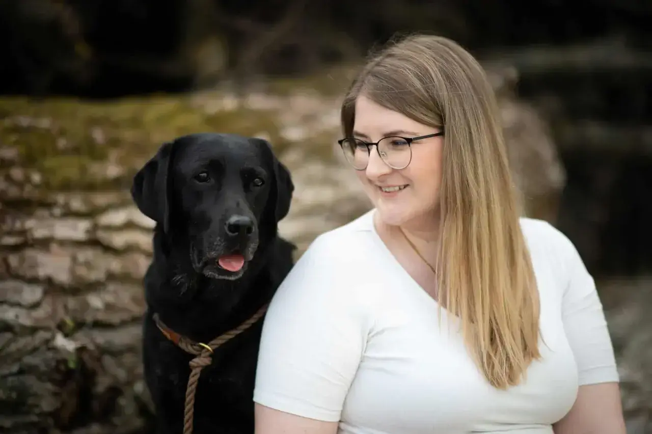 Ein schwarzer Labrador und eine Frau mit Brille lächeln. Perfekt für eine vorlage trainingsplan hund.