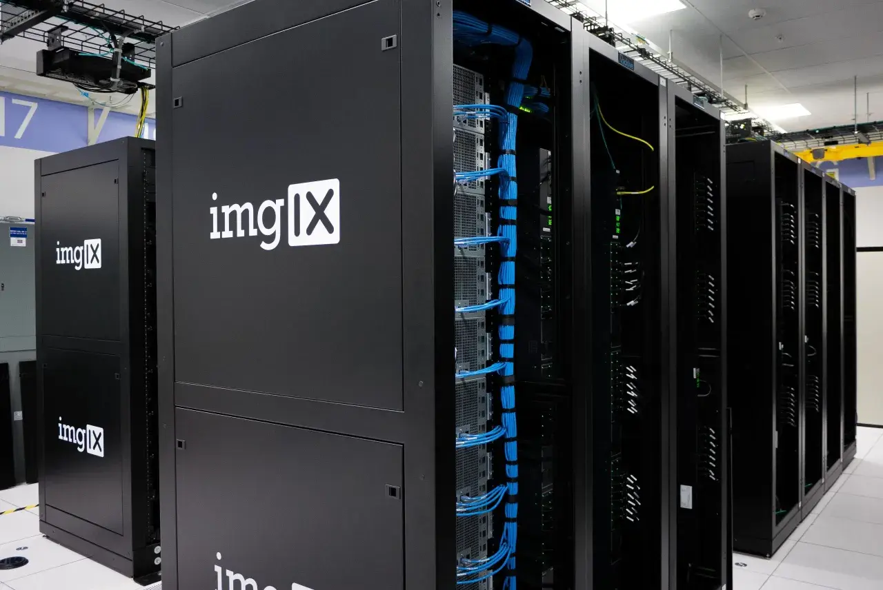 Des racks de serveurs noirs, dont un avec le logo "imgIX", remplis de câbles bleus et jaunes. C'est un peu ça, un serveur : le cœur de l'internet.