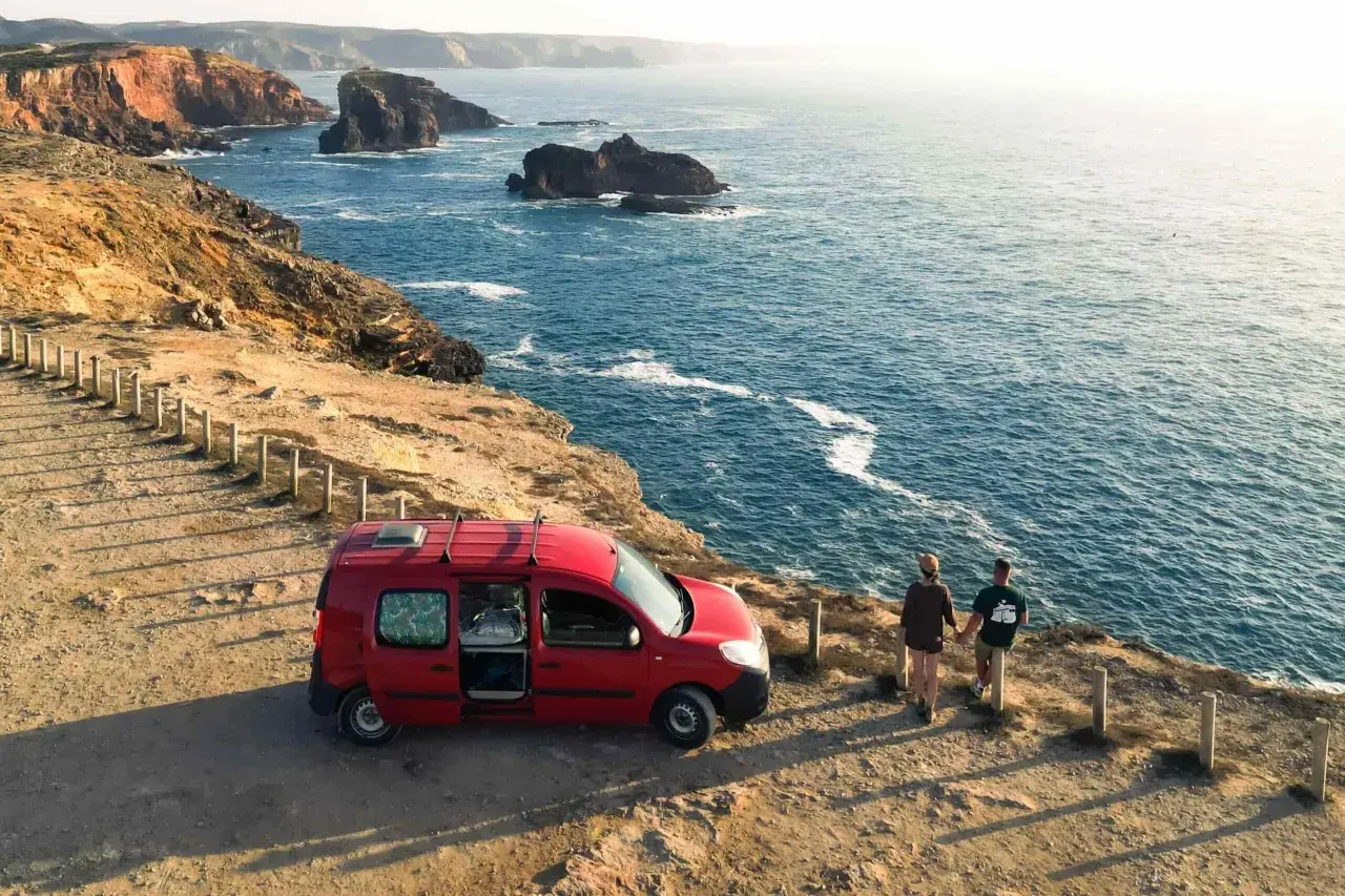 Para podróżuje kamperem po Portugalii, podziwiając skaliste wybrzeże i ocean.