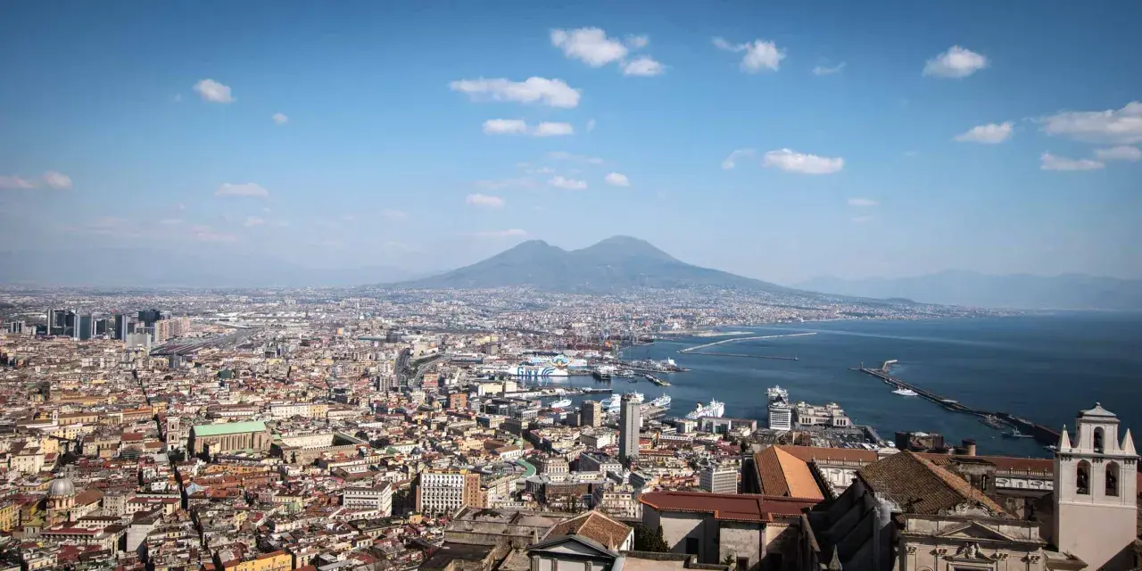 Panoramic view of Naples, Italy, with Mount Vesuvius in the background. Perfect for a Naples Italy itinerary, this vista captures the city's vibrant sprawl meeting the sea.