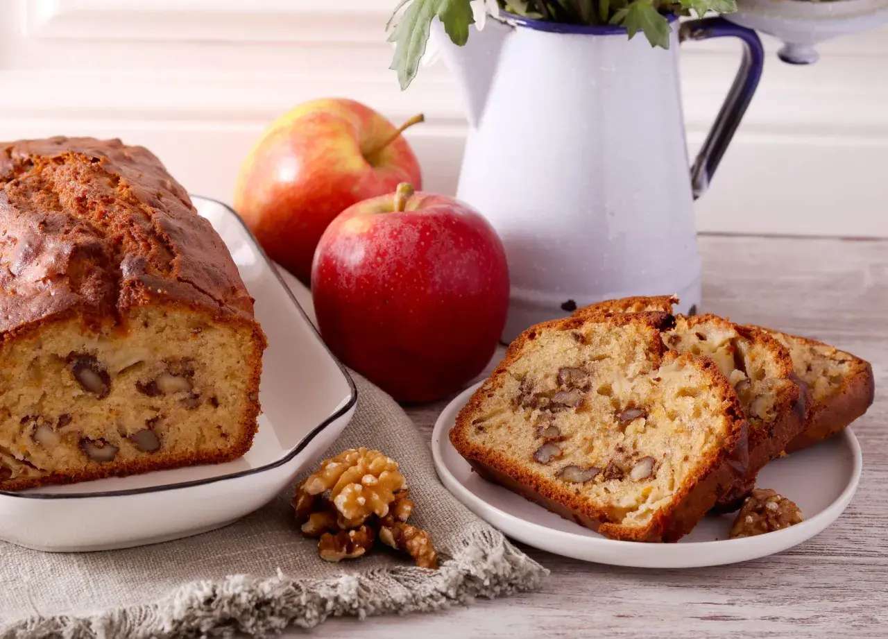 Un délicieux gâteau aux pommes et noix de grand-mère, avec des tranches présentées sur une assiette.