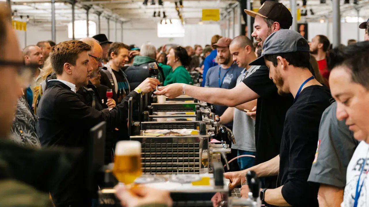 Folla a un evento di degustazione di birra a Mikkeller Copenhagen. Un uomo porge un bicchiere di birra scura.