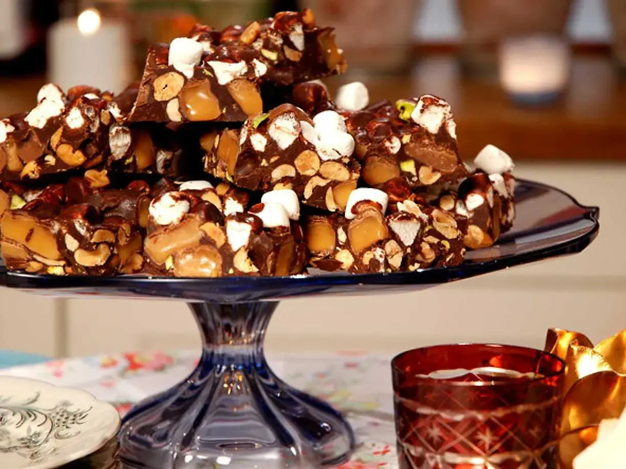 En hög med chokladbitar med nötter, karamell och marshmallows. En härlig rocky road-frestelse på ett blått fat.