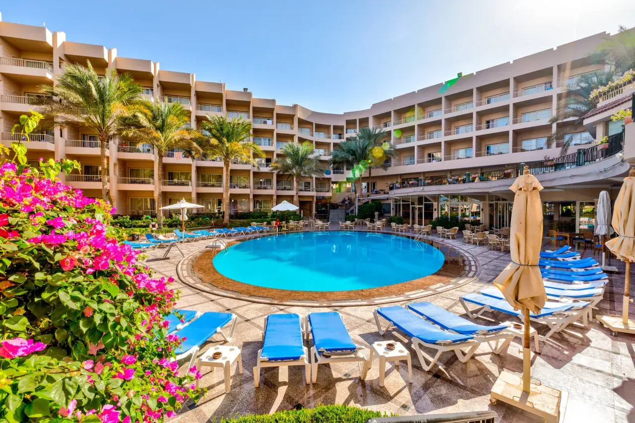 Basen hotelowy Beau Rivage z leżakami i palmami, otoczony budynkami hotelowymi.