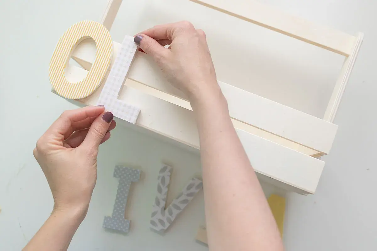 Manos decorando letras para manualidades de comunión, creando un detalle personal para un día especial.