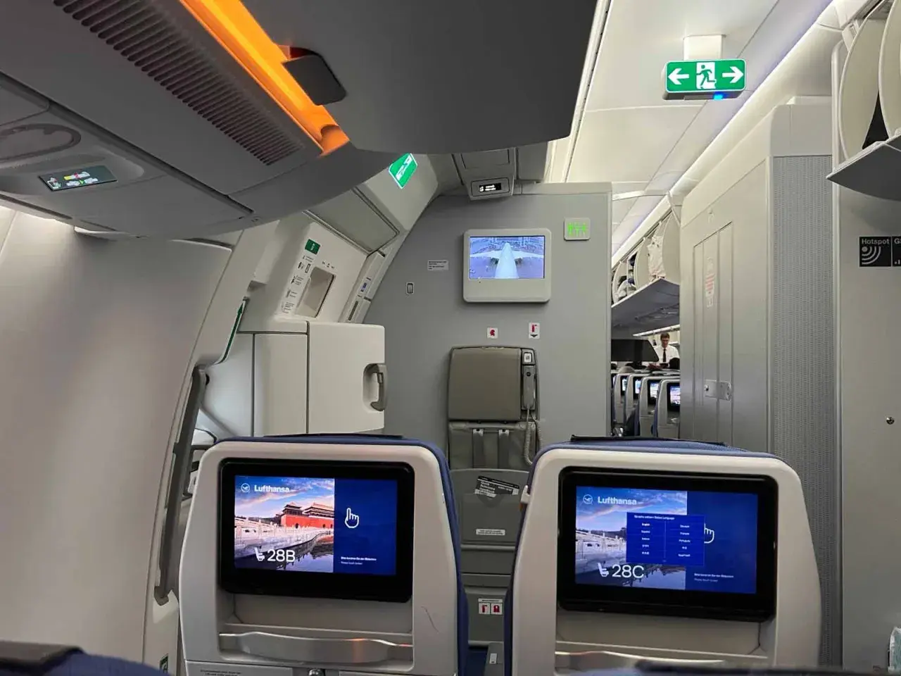 Blick in ein Flugzeug, wo man bequem sitzen kann. Die Bildschirme zeigen die Sitzplätze 28B und 28C.