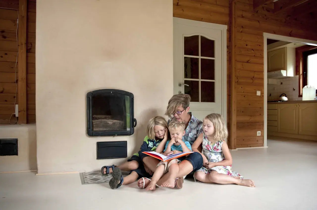 Een moeder leest voor aan haar drie kinderen bij de open haard. Een moment van rust en samenzijn, ontspullen voor en na een drukke dag.