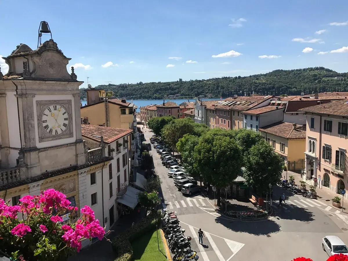 Vista dall'alto di Salò, con il lago sullo sfondo. Un orologio segna l'ora su un edificio storico.
