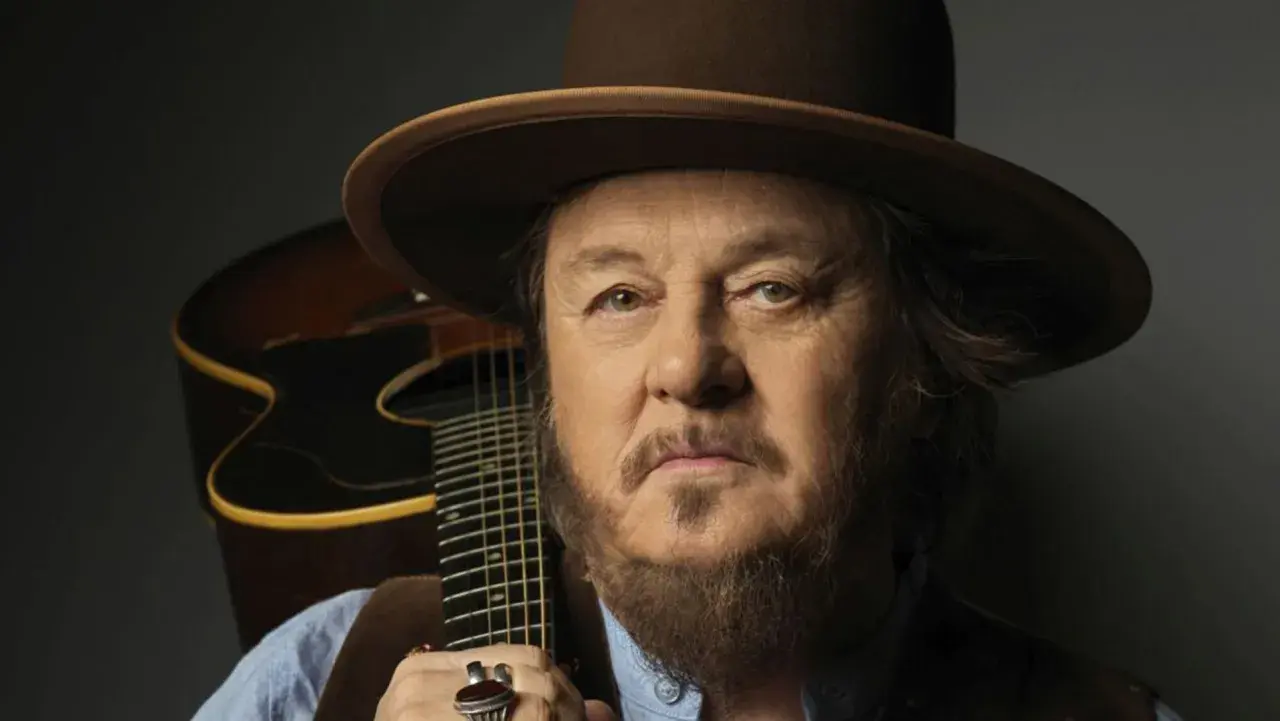 Mężczyzna w kapeluszu z gitarą, uosobienie Dire Straits Legacy.