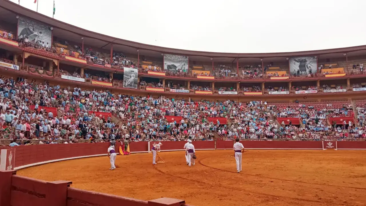 Toros en la grada seis. Multitud expectante en la plaza de toros, con toreros preparándose en la arena.