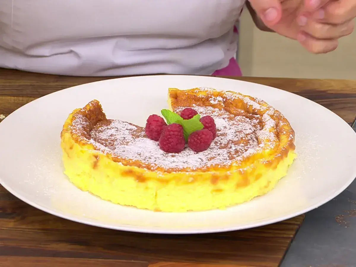 Tarta de queso Eva Arguiñano, dorada y espolvoreada con azúcar glas, coronada con frambuesas y menta. ¡Un postre irresistible!
