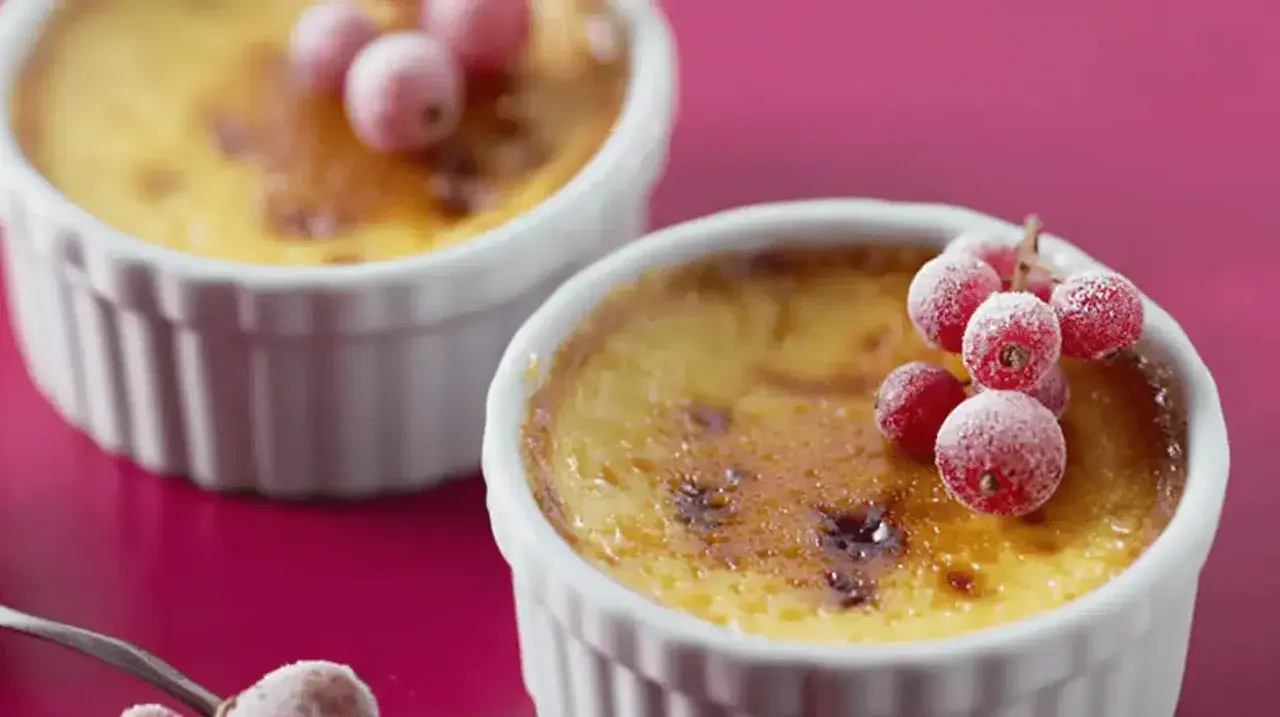 Deux flans aux œufs, dorés et caramélisés, ornés de groseilles givrées. Un délice visuel et gustatif.