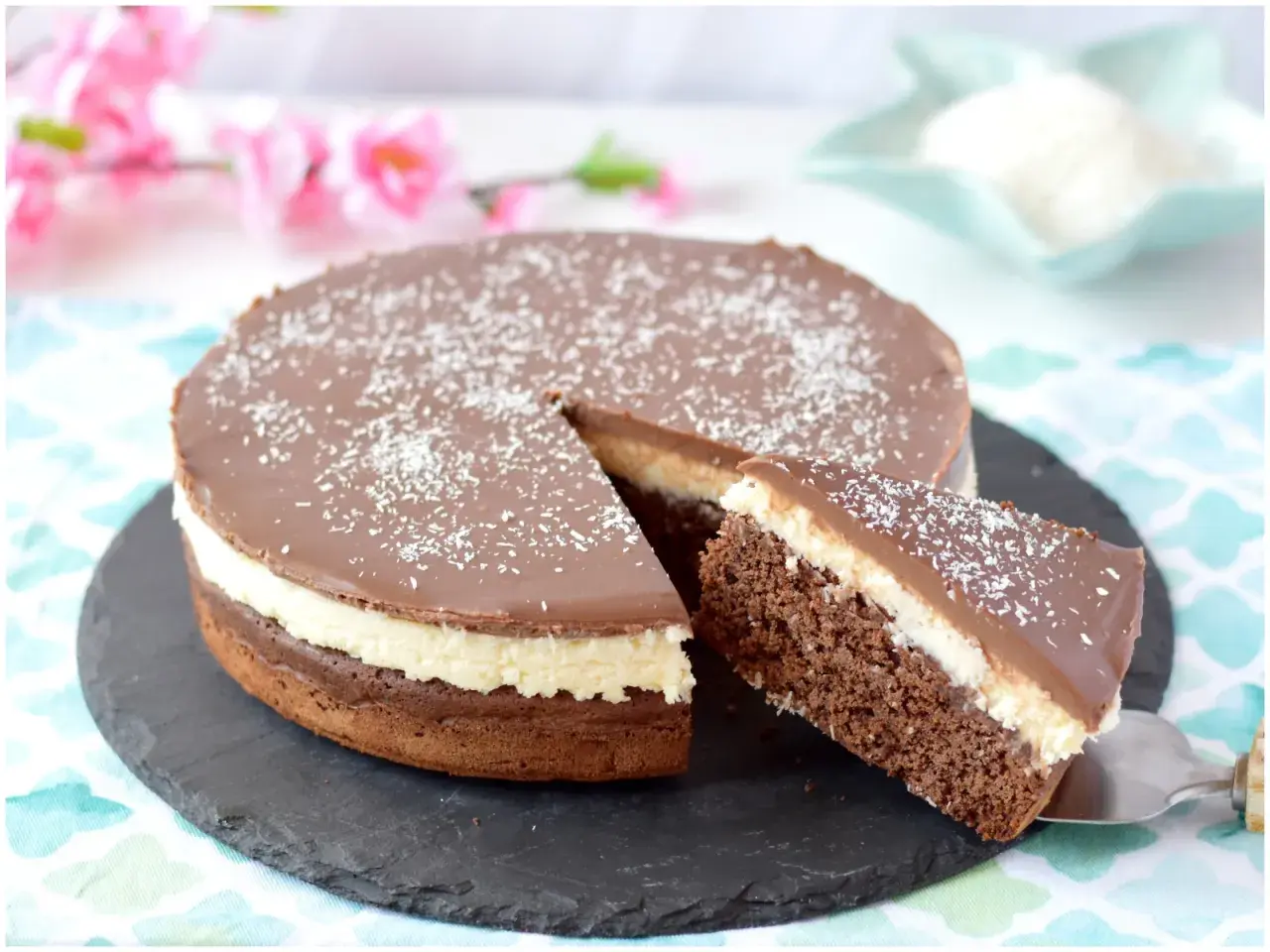 Deliziosa torta cocco e cioccolato con una fetta servita, cosparsa di cocco grattugiato.