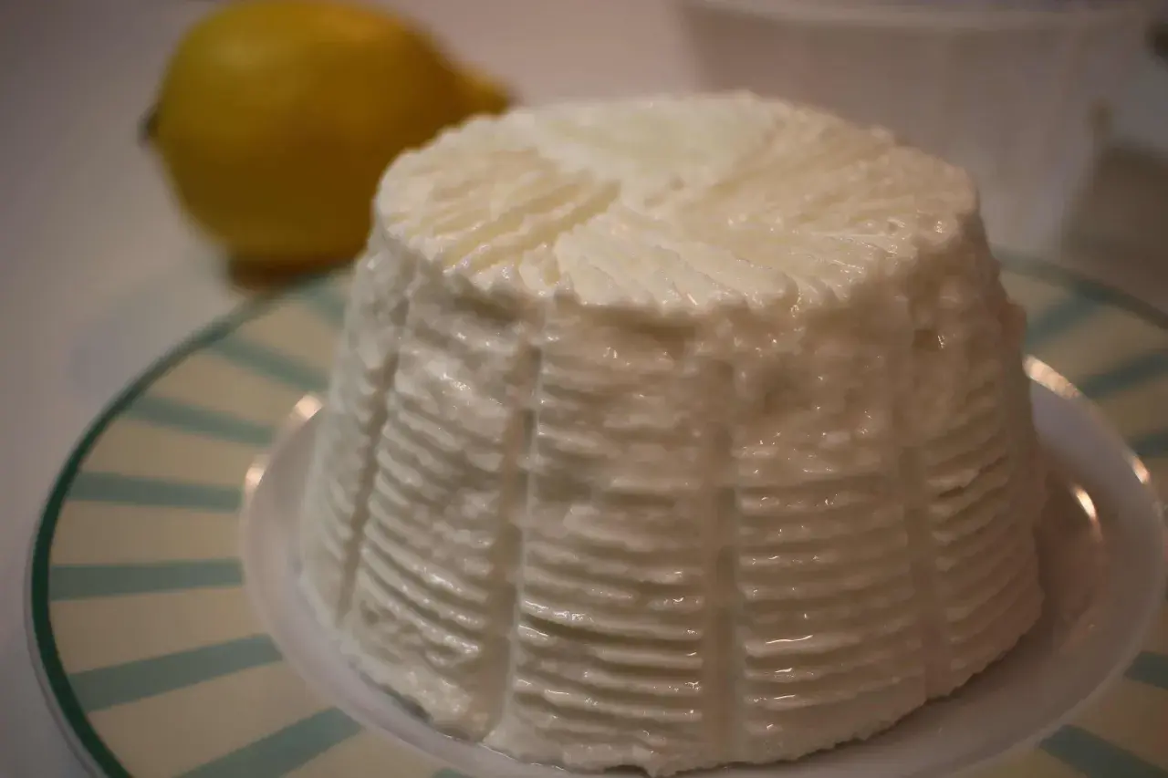 Un fiadone crémeux, prêt pour la recette des Carnets de Julie, avec un citron flou en arrière-plan.
