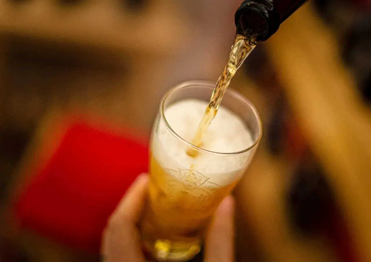 Z butelki leje się złociste piwo Peroni do szklanki, tworząc obfitą pianę.