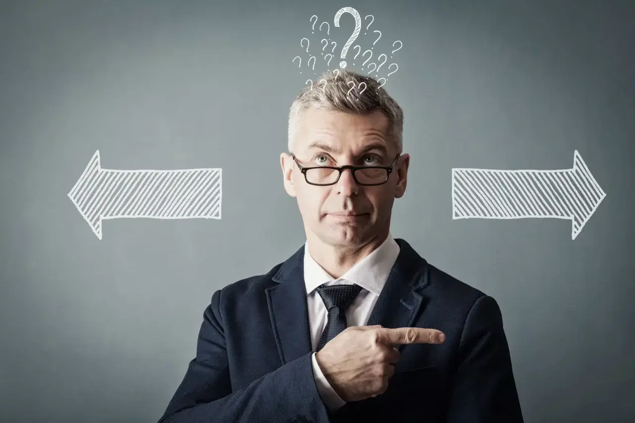 Un homme d'affaires réfléchit, entouré de points d'interrogation et de flèches. Il cherche la meilleure solution, peut-être avec un logiciel GED.