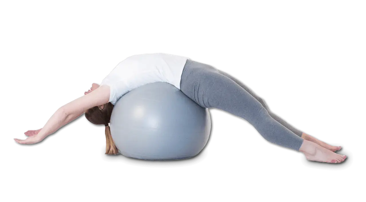 Une femme s'étire sur un ballon de gym, le dos cambré, dans une posture qui pourrait aider à corriger une cyphose.