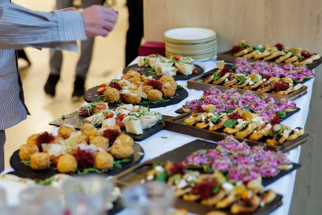 Pyszny catering na święta bożego narodzenia: przekąski z kulkami serowymi, rolkami i kanapeczkami z różowymi kiełkami.