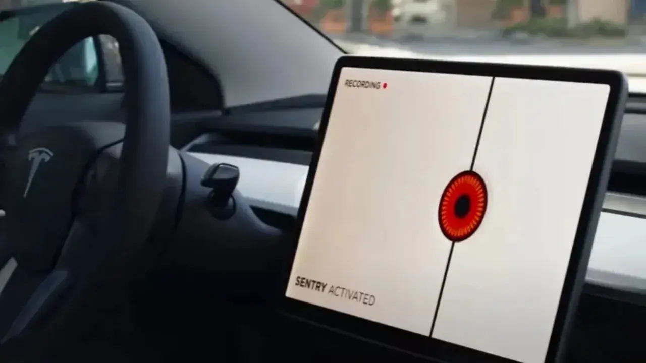 Teslas mittskärm visar "SENTRY ACTIVATED" med en röd ögonliknande ikon. Bilen är redo att agera som en vaktpost.