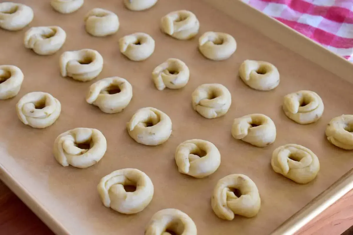 Små, ringformade taralli ligger redo på en bakplåt. Ett perfekt taralli recept för hembakade godsaker.