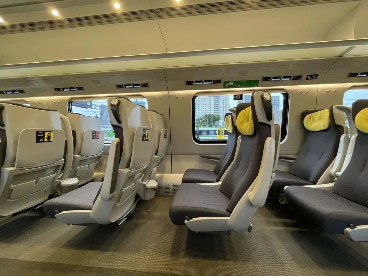 Wnętrze pociągu Pendolino. Fotele klasy 1 i 2, wygodne, z żółtymi zagłówkami, czekają na pasażerów.