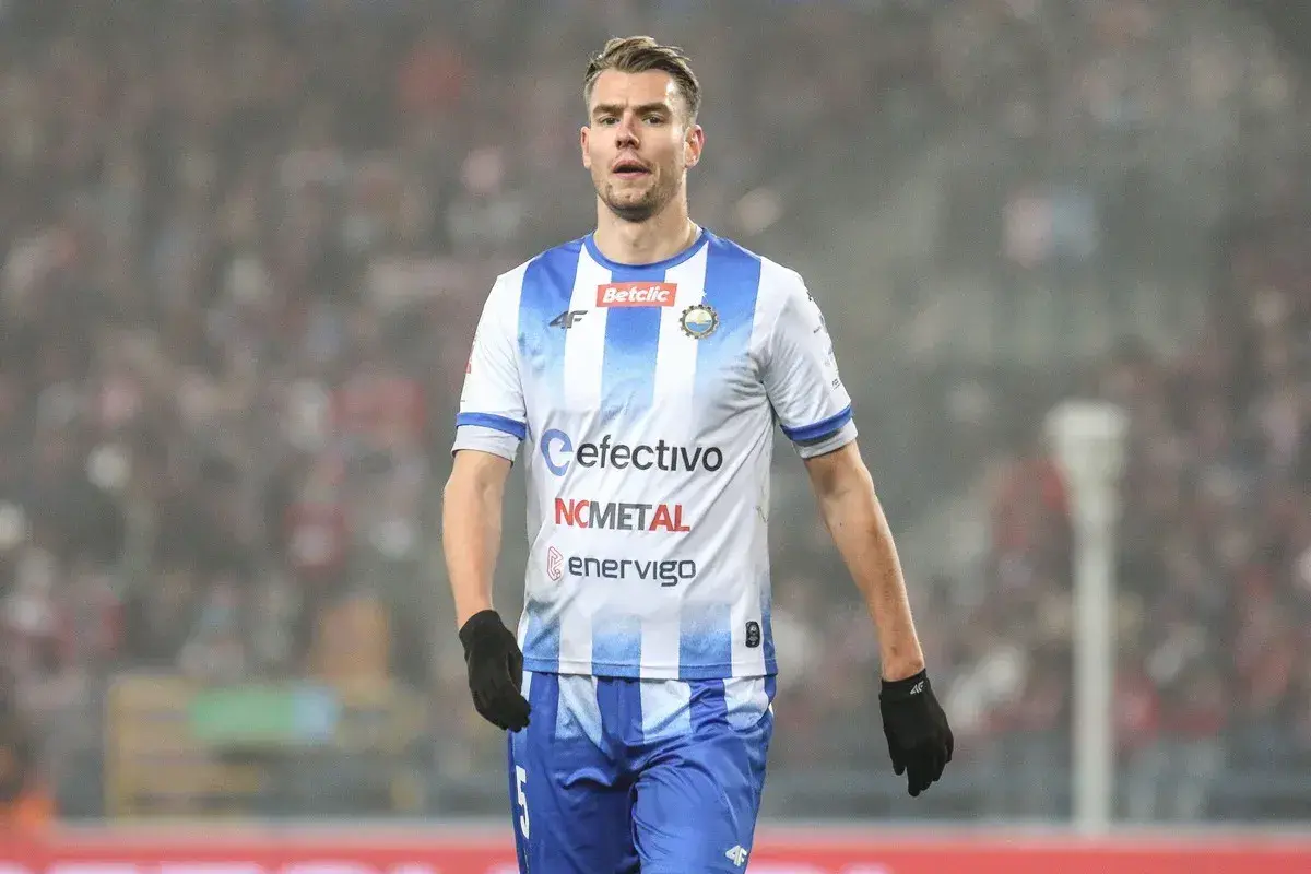 Piłkarz ŁKS Łódź w białej koszulce w niebieskie pasy, gotowy do gry. Rankingi stal Mielec – ŁKS Łódź.