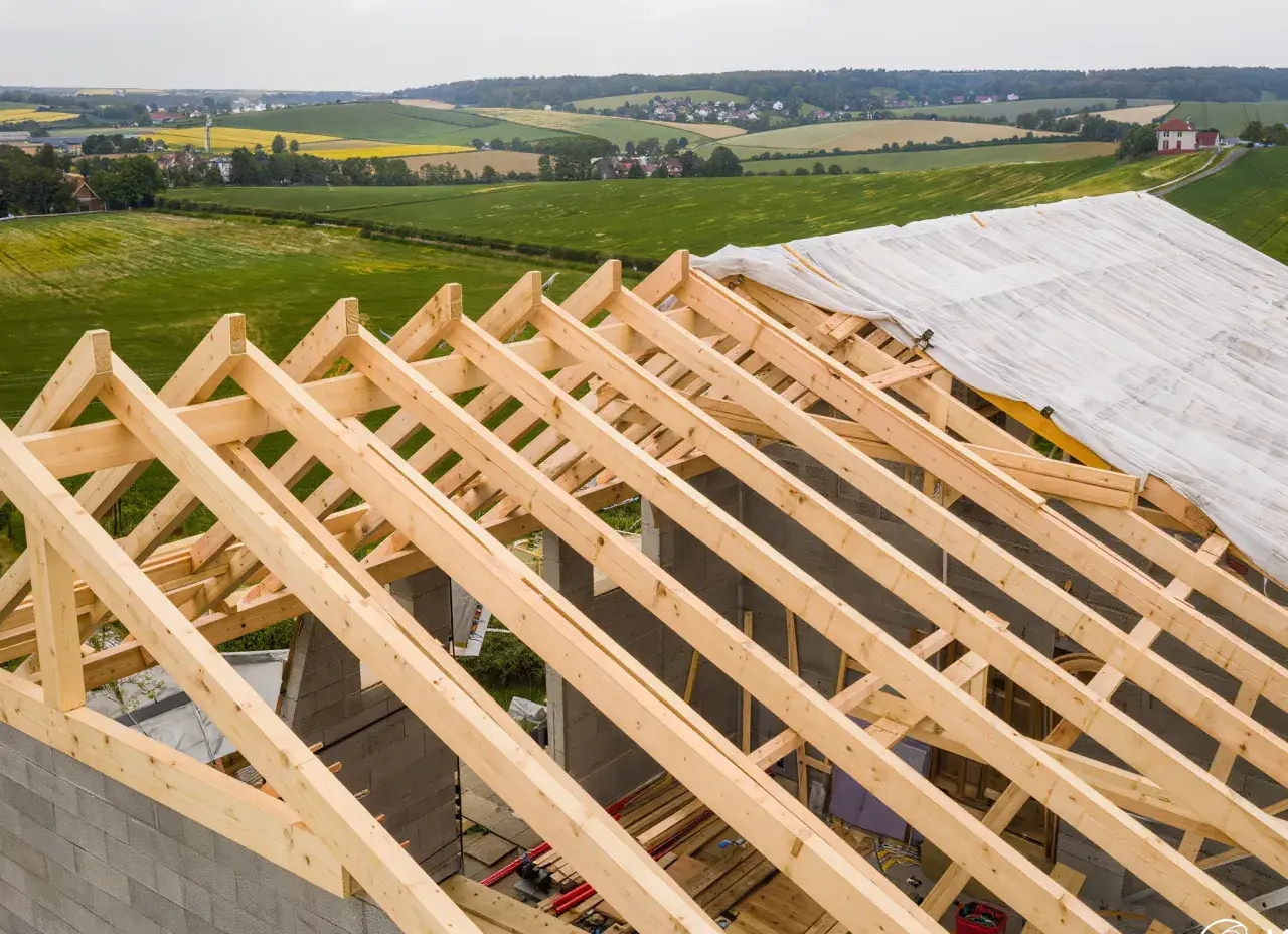 Charpente en bois sur un chantier, recouverte d'une bâche. La question est : combien de temps peut-on laisser une charpente dehors avant qu'elle ne se dégrade ?