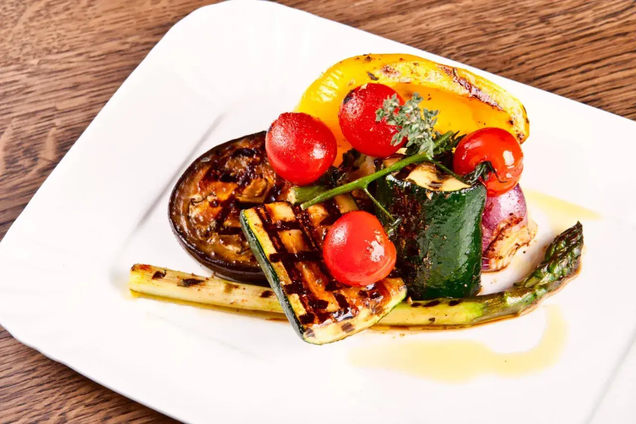 Légumes grillés au barbecue : courgettes, aubergines, poivrons, asperges, oignons rouges et tomates cerises.