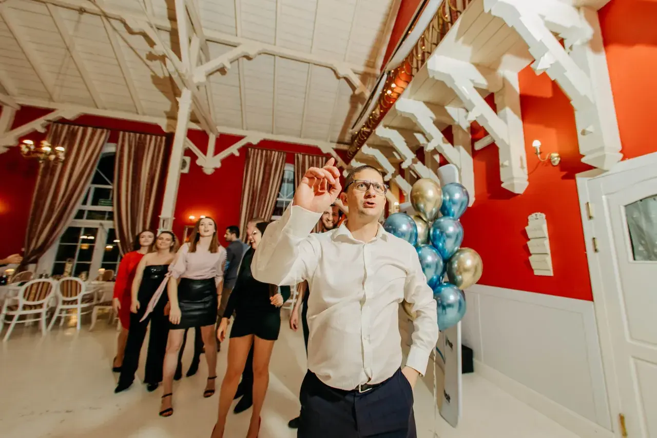 Ludzie tańczą na imprezie firmowej. W tle balony i dekoracje, świetne pomysły na jubileusz firmy.