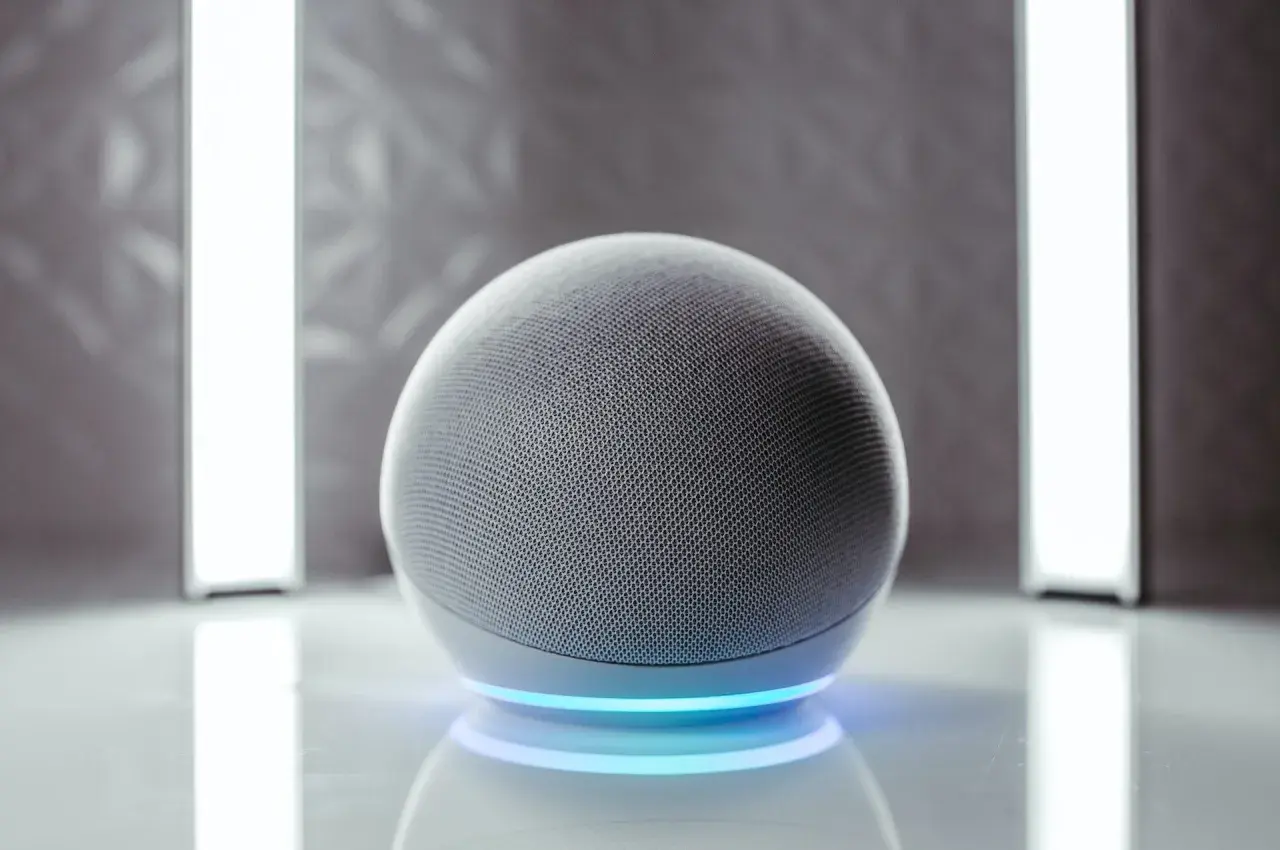 Altavoz esférico gris con anillo de luz azul. Listo para activar Alexa.