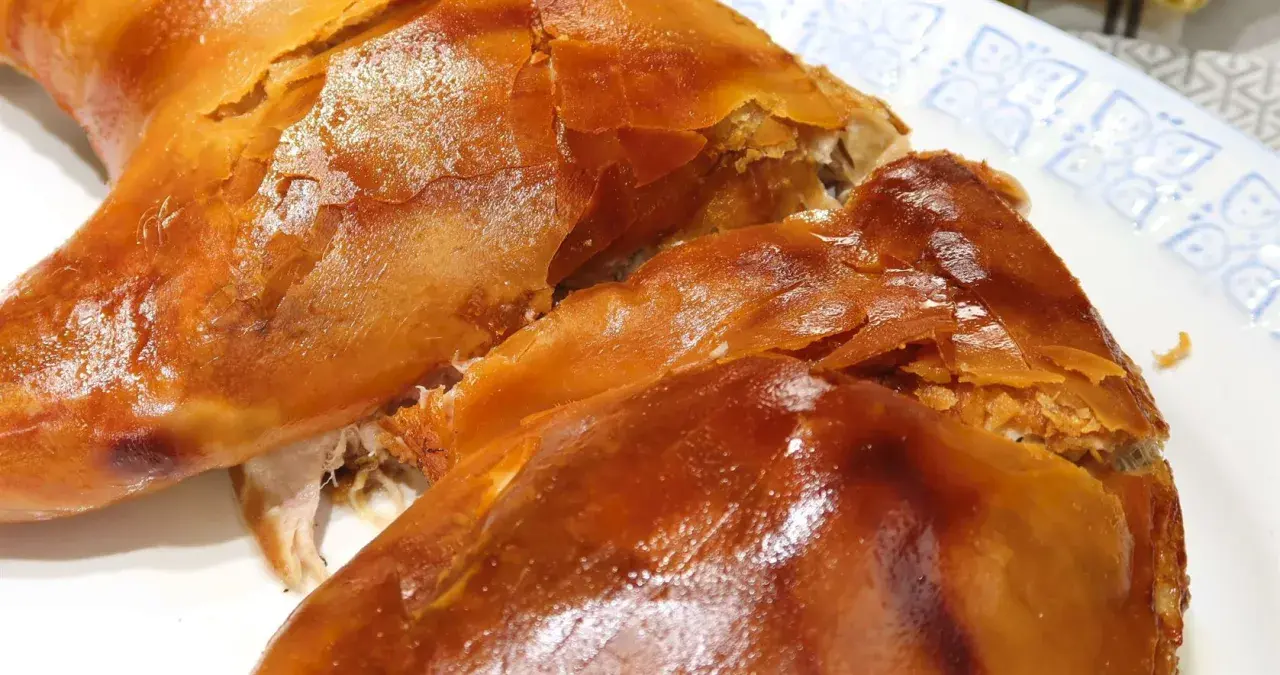 Un crujiente cochinillo al horno, con piel dorada y carne jugosa, listo para ser disfrutado.