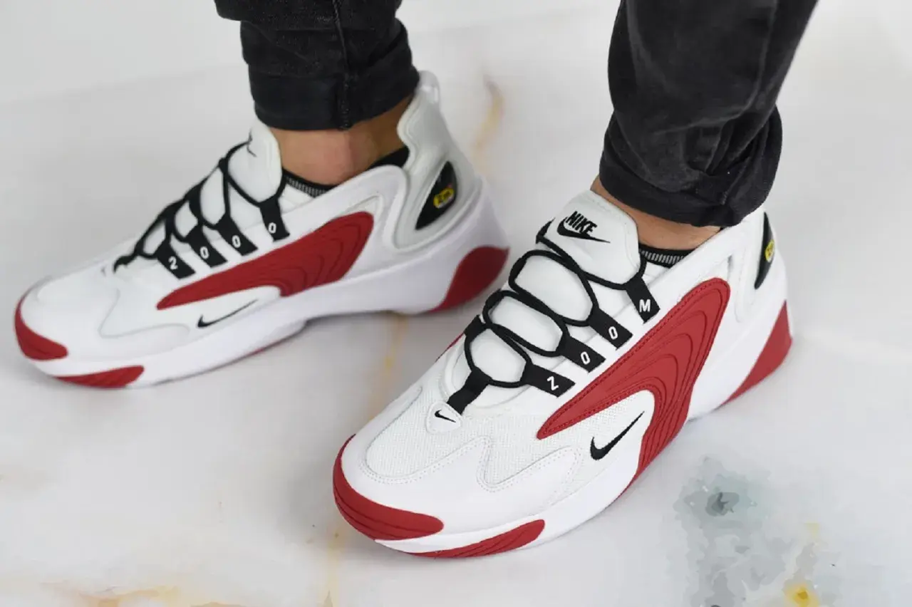 Białe buty Nike z czerwonymi akcentami i czarnymi sznurówkami. Numer "2000" na sznurówkach nawiązuje do historii marki Nike.