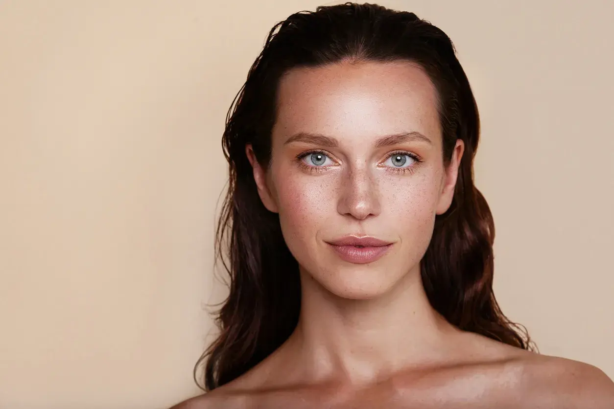 Un maquillage subtil pour agrandir les yeux, mettant en valeur des iris bleus et des taches de rousseur naturelles.