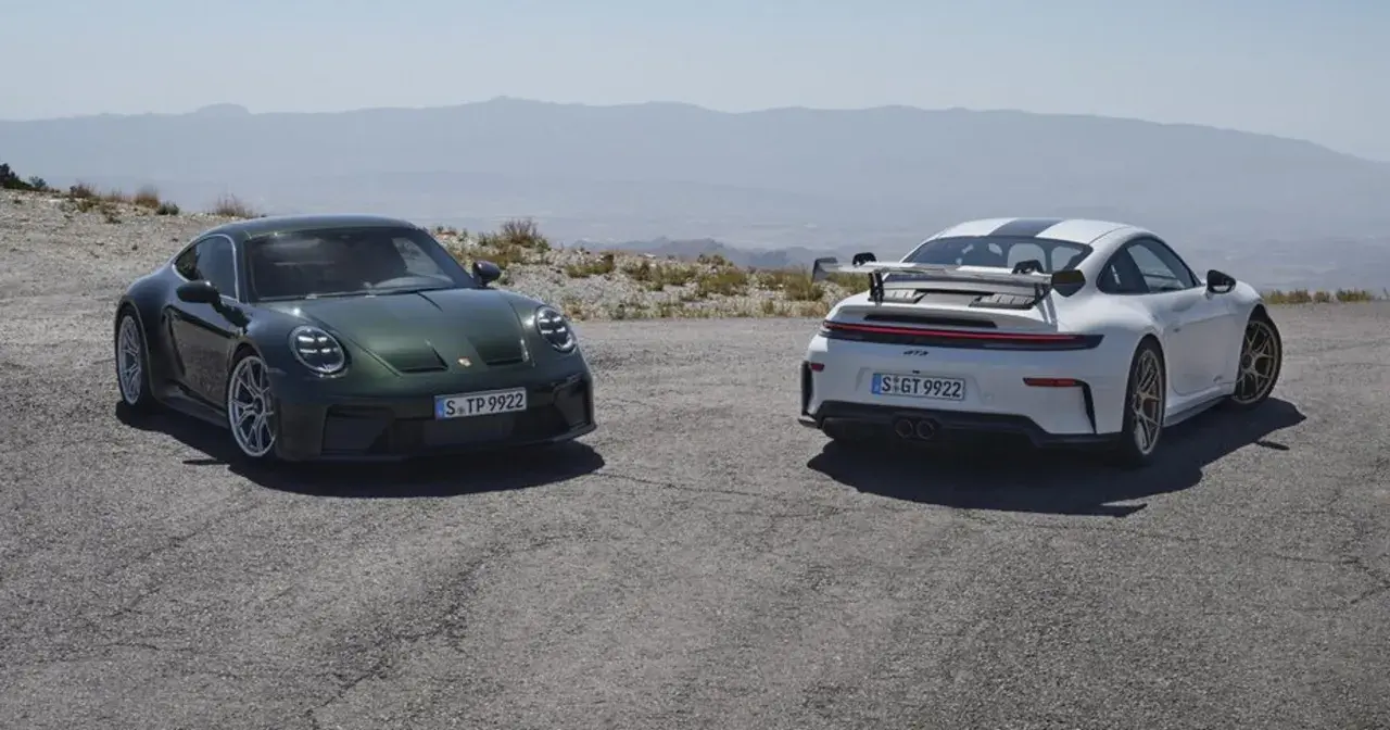 Dwa Porsche 911 GT3, zielone i białe, stoją na górskiej drodze.