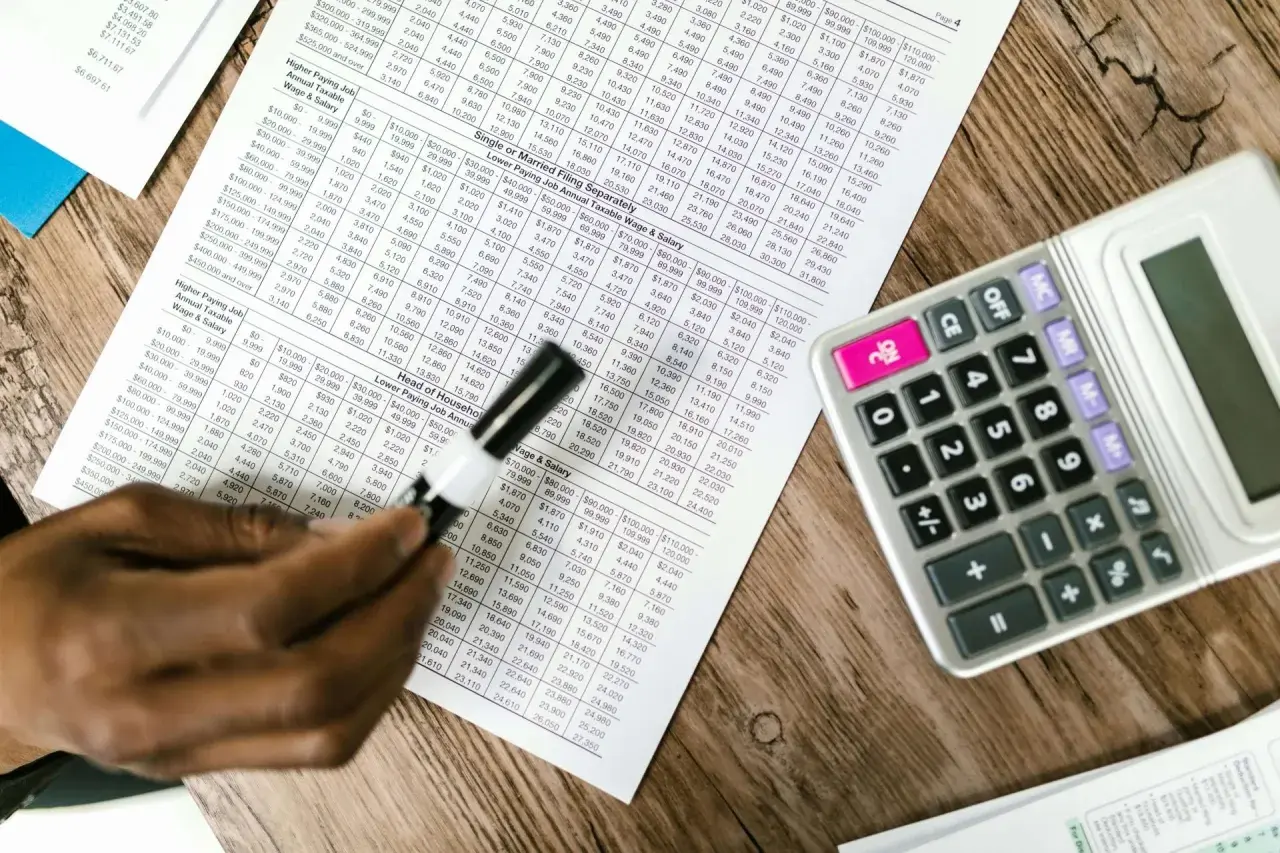 Tabela z danymi finansowymi, kalkulator i ręka analizująca układ rodzajowy kosztów.
