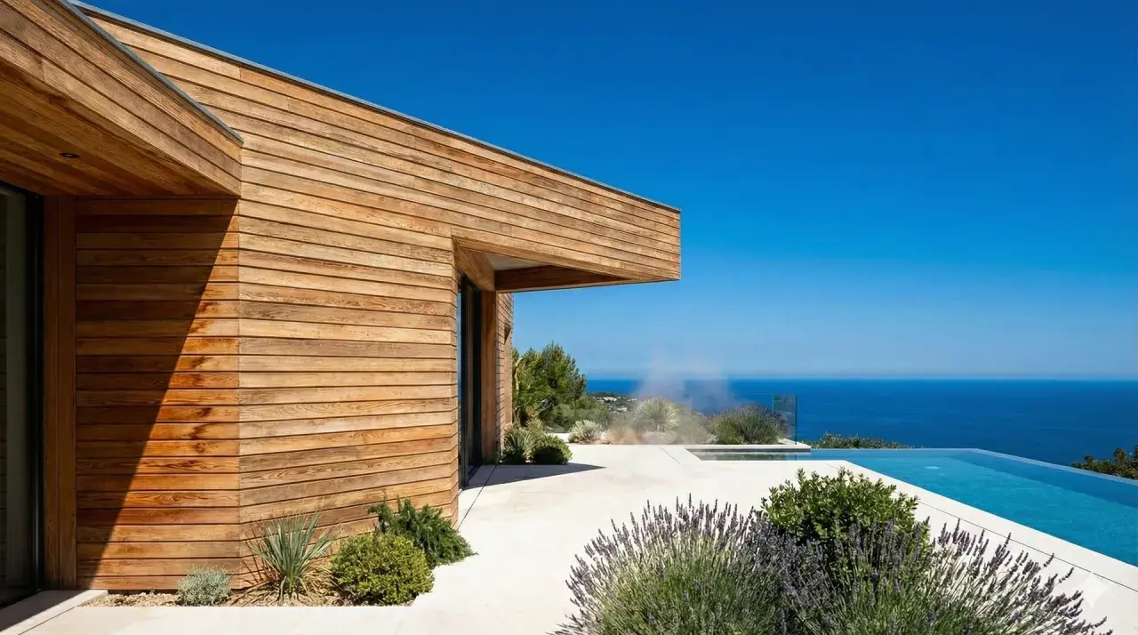 Maison moderne avec bardage bois, piscine à débordement et vue mer. Le choix du bois pour ossature bois est crucial pour ce style.